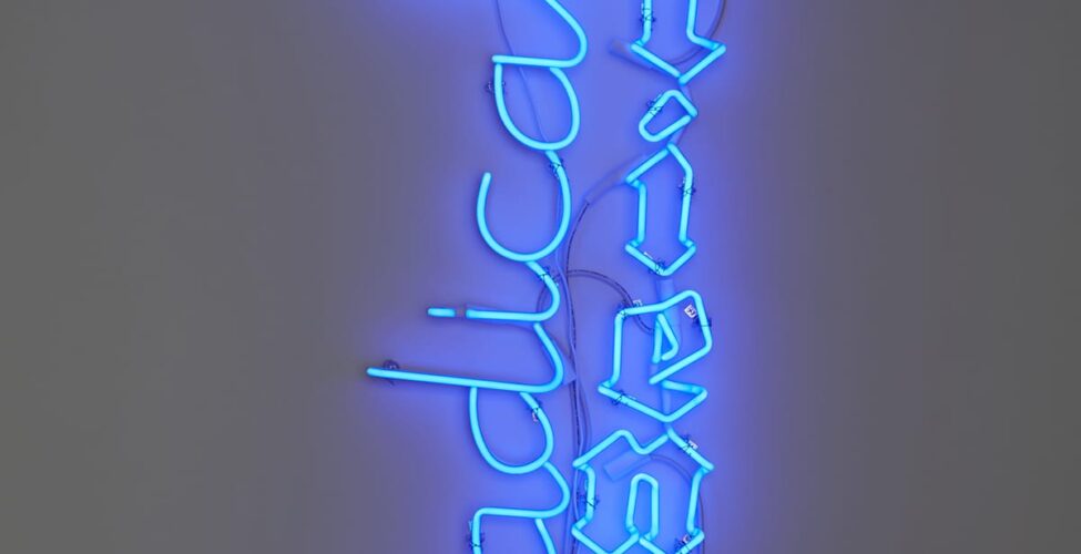 Blue neon sign with the word “Radical” in cursive positioned to the left of “Patience” in Gothic black letter and adjacent to a white analog clock that displayed 12:10 at the time of the photo.