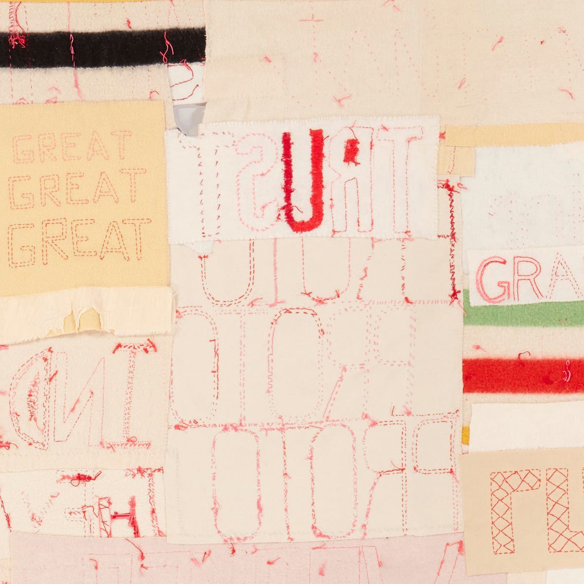 Detail of the back of the work showing words in reverse, knots, and loose threads. In contrast to the reversed lettering, at upper left the words Great, Great, Great are stacked one on top of the other increasing in size. A black and cream striped blanket fragment is at top left and a green, cream, and red blanket portion appears at right near the bottom of the detail.