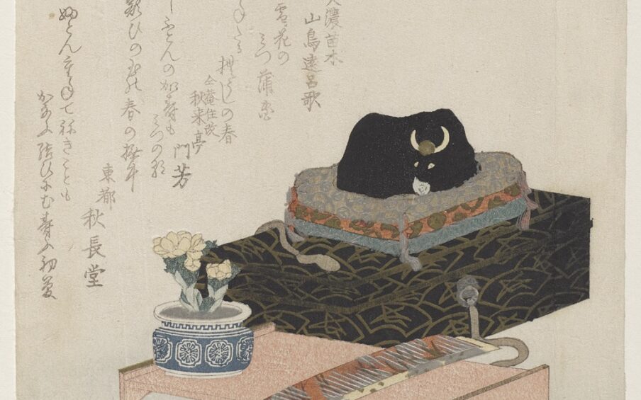 1. Ox figurine and writing desk, Keisai Eisen, 1 9/16 x 6 11/16 inches, color woodblock print with metallic pigments and embossing on paper. A vertical rectangular print featuring a black ox figurine resting on top of small futon mats atop a writing box near a writing table and other objects. The vignette is situated in the lower two thirds of the print. The sleeping ox figurine sits on three small multi-colored futon mats which in turn rests on a black and gold patterned writing box. In front of the box is a pale peach writing desk with short legs showing a fan shaped cut out on the sides. Folded fans lay near the desk and a blooming flower in a blue and white pot sits on the edge of the desk. Poems written in Japanese climb from the center left of the print to the upper center. 2. The print is seen in axial light showing the gold and silver details on the objects. The black ox now appears to be charcoal in color and outlined in black. 3. Detail of the ox figurine and futon mats. The ox’s legs, tail, skin folds and facial features are outlined in black. It has ivory-colored horns on either side of a gold disc on its forehead and gold eyes. The futon mats are each have a different pattern and color: silver on beige, gold on rust and silver on teal.