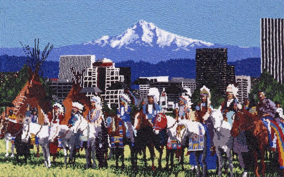 The Gathering, Marcus Amerman, 10 1/8 x 17 inches, glass beads on cotton cloth. A horizontal, rectangular work depicting a grouping of individuals on horseback arranged in a line in front of the Portland skyline with Mt. Hood in the distance. The grouping takes up the lower half of the work. They are shown on a patch of pale green grass wearing white feather headdresses and finery in blues, brick red, white and yellow. Their brown and white horses are adorned in similar colors. Just behind the group on the left are 2 brown tipis. The cityscape in the middle ground is composed of geometric buildings beaded in gray, white and black set against the blue and white mountains and blue sky in the upper half.