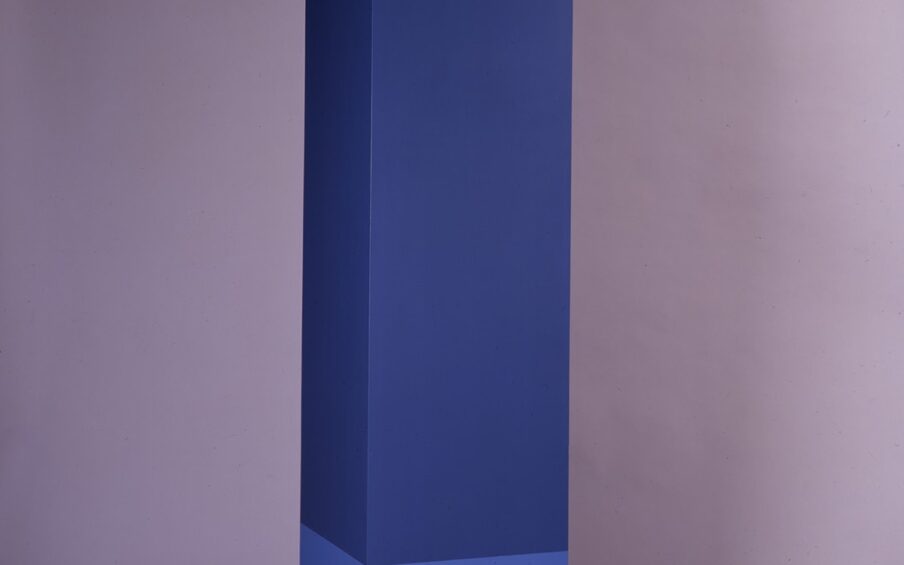 Image description: Anne Pruitt. Bonne. Acrylic on wood. 81 1/4 x 18 x 18 inches. A vertical sculpture consisting of a tall, rectangular column on top of a slightly smaller, square base. The top eighth of the sculpture is bright, winter white. The middle section, about five eighths of the work, is a deep, navy blue. The lower section is medium blue. The colors are cleanly differentiated, creating distinct segments. About one foot above the ground, midway through the medium blue section, a thin lip distinguishes the base. The paint has been applied evenly and smoothly.
