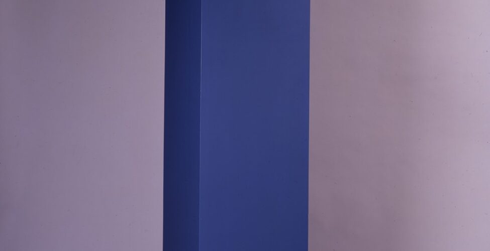 Image description: Anne Pruitt. Bonne. Acrylic on wood. 81 1/4 x 18 x 18 inches. A vertical sculpture consisting of a tall, rectangular column on top of a slightly smaller, square base. The top eighth of the sculpture is bright, winter white. The middle section, about five eighths of the work, is a deep, navy blue. The lower section is medium blue. The colors are cleanly differentiated, creating distinct segments. About one foot above the ground, midway through the medium blue section, a thin lip distinguishes the base. The paint has been applied evenly and smoothly.