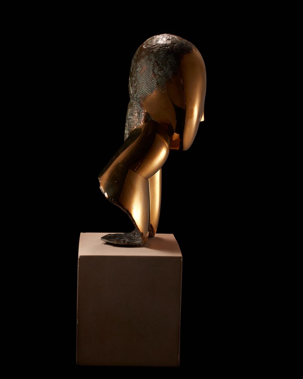 Image description: Muse, Constantin Brancusi, bronze on limestone base, 19 1/2 x 10 x 5 inches. A smooth, bronze, stylized bust of a woman’s head, elongated neck and shoulder. Front view: The woman’s egg-shaped head is smooth except for a raised V shape in the center representing the brow and finishing in a delicate nose. A small mouth is the only other feature on the face. Hair is suggested with rough, textured lines incised into the crown of the head. This texture appears darker than the glossy golden bronze face. A long neck extends from the head at left and is attached to a sloping shoulder. At right, the head seems to rest on a hand and forearm that extends to join the shoulder. The bottom edge of the sculpture has a rough and unfinished appearance. The bust rests on a gray cube of limestone that is juts a bit wider than the sculpture and about half as high. Left profile view: A smooth egg-shaped head smooth except for a small nose at the lower third of the profile. An simple C shaped ear is positioned below the textured hair. A gracefully shaped neck extends forward from a wedge-shaped shoulder. The bronze material folds back on itself, exposing rough edges, to rest on the base. Rear view: The textured hair appears to lengthen past the shoulder area ending in a blunt point. The sculpture’s shoulders fan out into a cone like structure that opens at an angle to expose the unpolished bronze inside. Right profile view: The hand and forearm shapes are visible from this view represented by simple elongated oval shape, a crease at the wrist giving definition to the two parts.