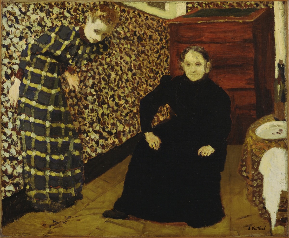 Image description: Vuillard, Interior, Mother and Sister of the Artist, 1893, oil on canvas. This painting is crowded with busy patterns and two women looking out towards the viewer. The young woman on the left wears a hunter green, yellow and white plaid dress and is leaning against the wall while bending forward at the waist as if to stay in the painting. The wall behind her is patterned of many colored splotches including white, crimson, yellow and dark green. Despite competing patterns the young woman almost blends into the wall, save for her pale face and hands. An older woman is seated on a chair in the middle of the space. She is wearing an all black dress and her pale face and hands offer contrast. The rug beneath them is a tan color and appears to have a subtle pattern to it. At the back of the room, in the corner, is a warm brown wooden dresser with drawers and on the far right of the scene, next to the seated woman is a round table covered with a brown, yellow, orange and cream patterned tablecloth. On top of the table sits a large wine bottle, an empty white plate and a crumpled white napkin.
