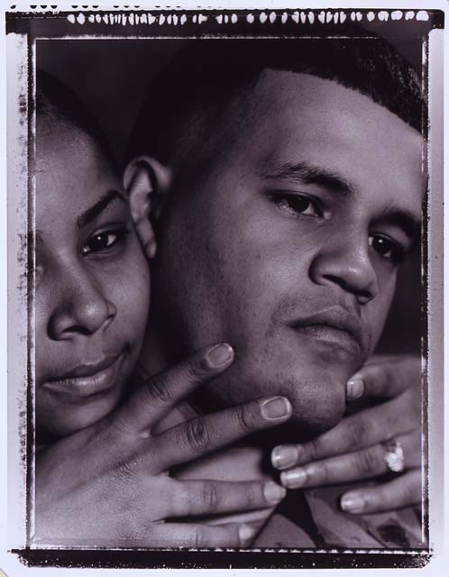 Suzanne Opton, Soldier: Jimenez—365 Days in Iraq, Fort Drum, New York, 2005, c-print, 18 x 14 ¼ in. Closely cropped vertical b&w photo of a soldier turned to the viewer’s right while his partner’s head is next to his and both hands tenderly positioning his chin revealing a wedding band.