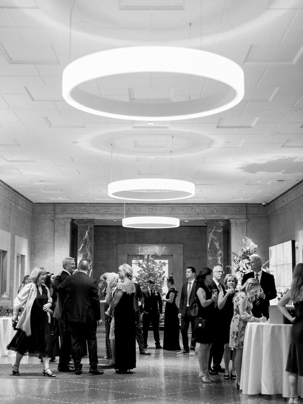 Black and white photo of people in dresses and suits gathered in the Mark Building lobby