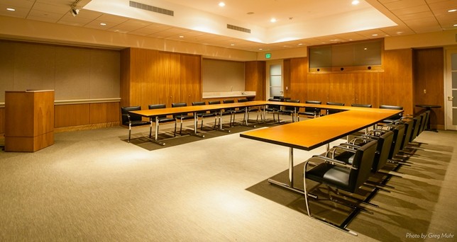 A conference room with a U-shaped conference table surrounded by chairs.