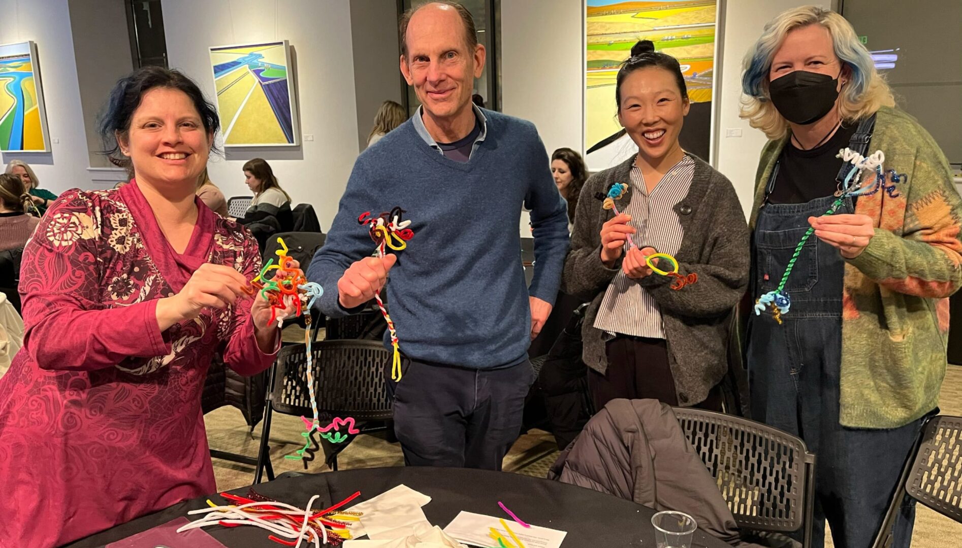 Photo of four adults holding up pipe cleaner art