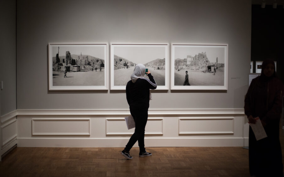 Person viewing photographs on a gallery wall.