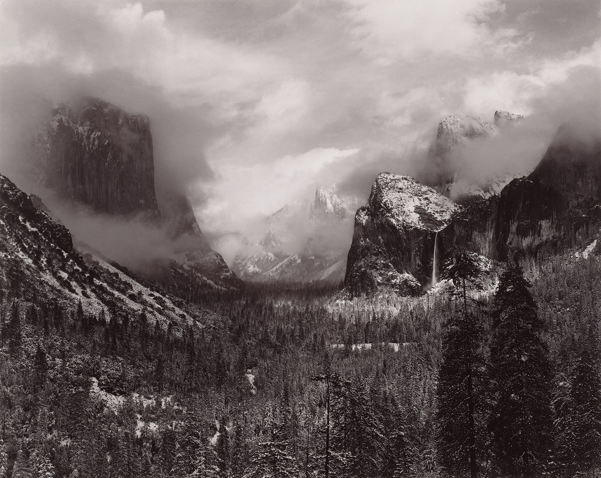 A sepia toned photograph of a Yosemite valley with clouds gathering