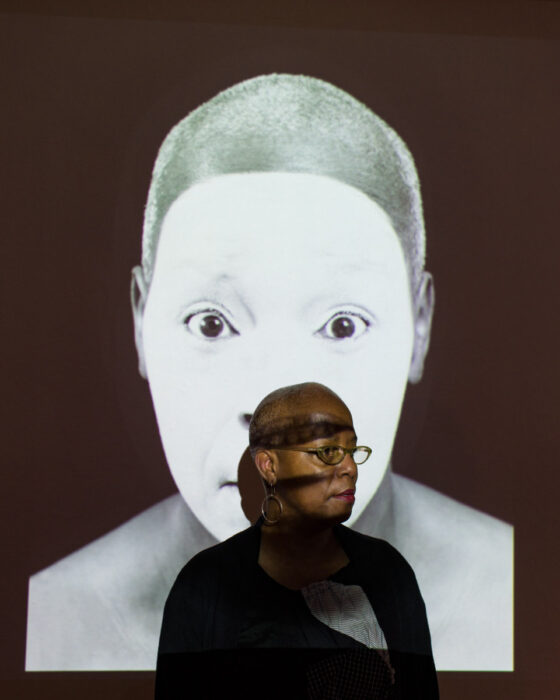 Photo by Briana Cerezo of artist Sharyll Burroughs with When Blackface is Butoh video installation.