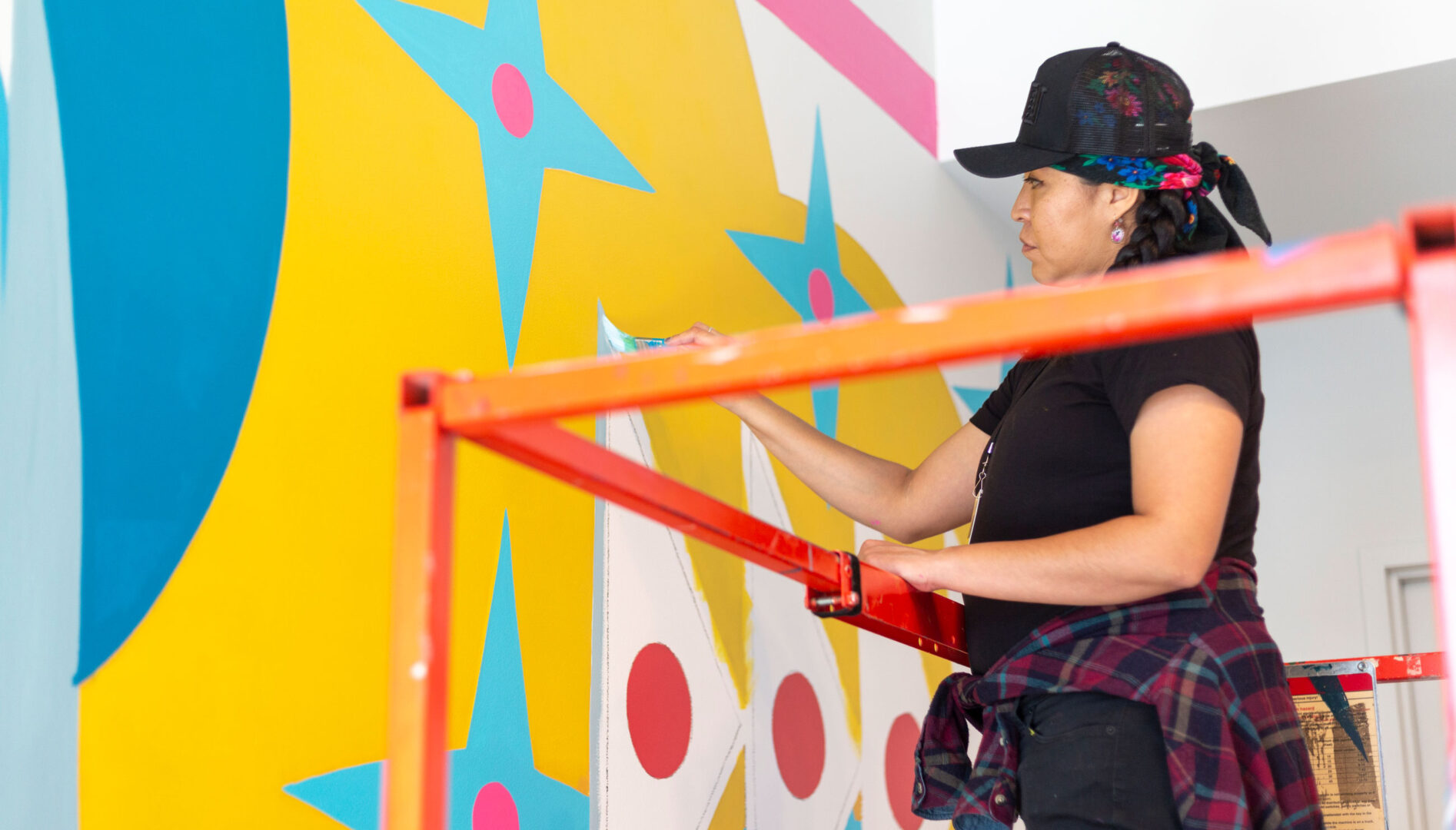 Artist Lynnette Haozous working on the mural “Into the Sun,” 2021