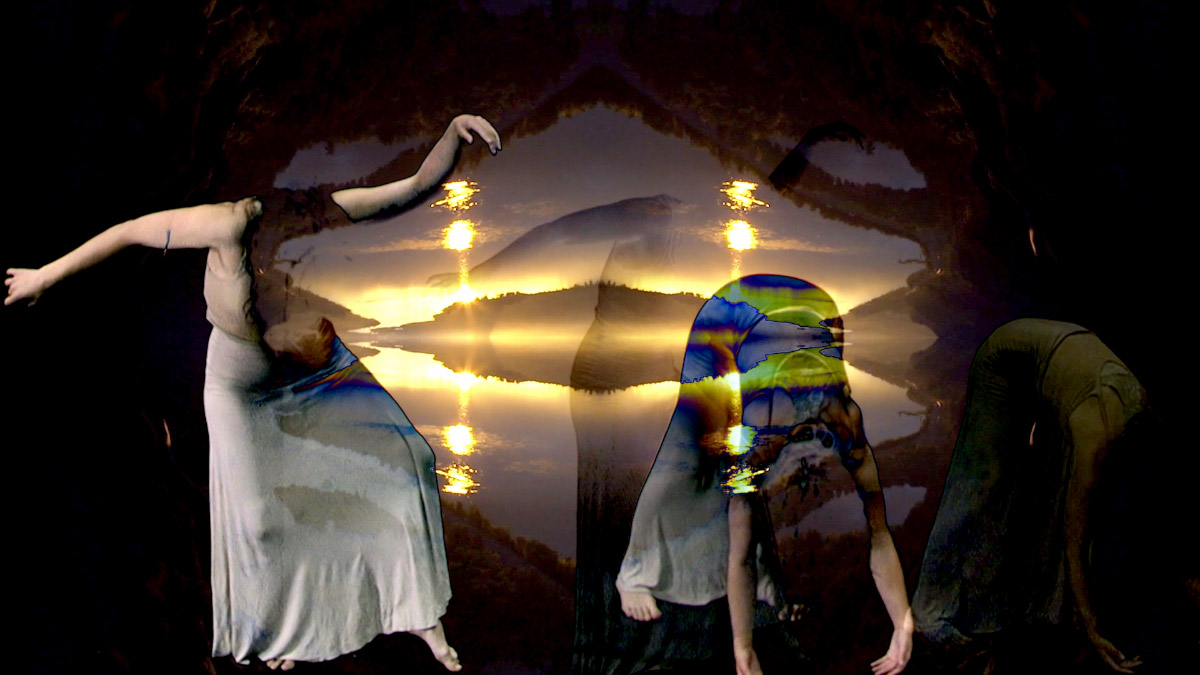 An image of two women in white dresses dancing in front of the projection of lights and mountains