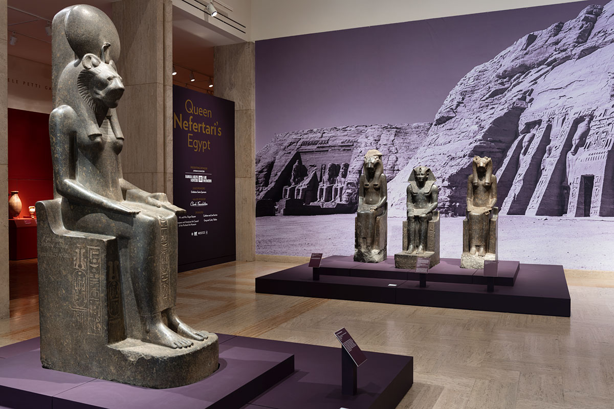 Gallery with Egyptian statues and an image of pyramids on the back wall