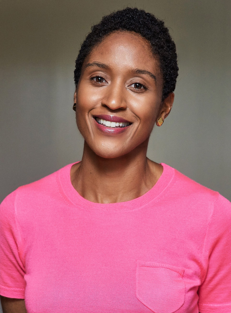 A Black woman with short hair, smiling and wearing a bright pink shirt.