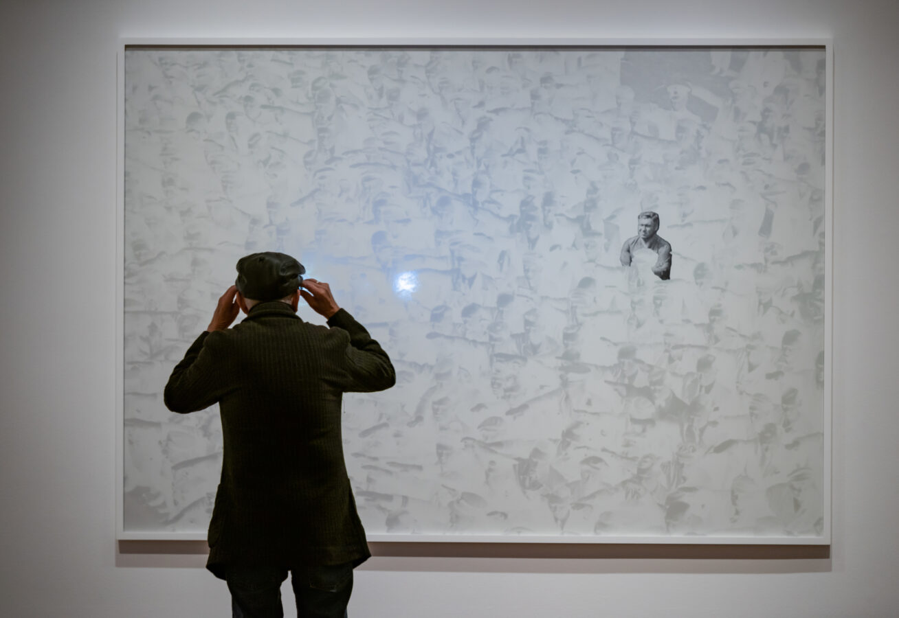 Photo of a person looking at a large artwork on the wall.