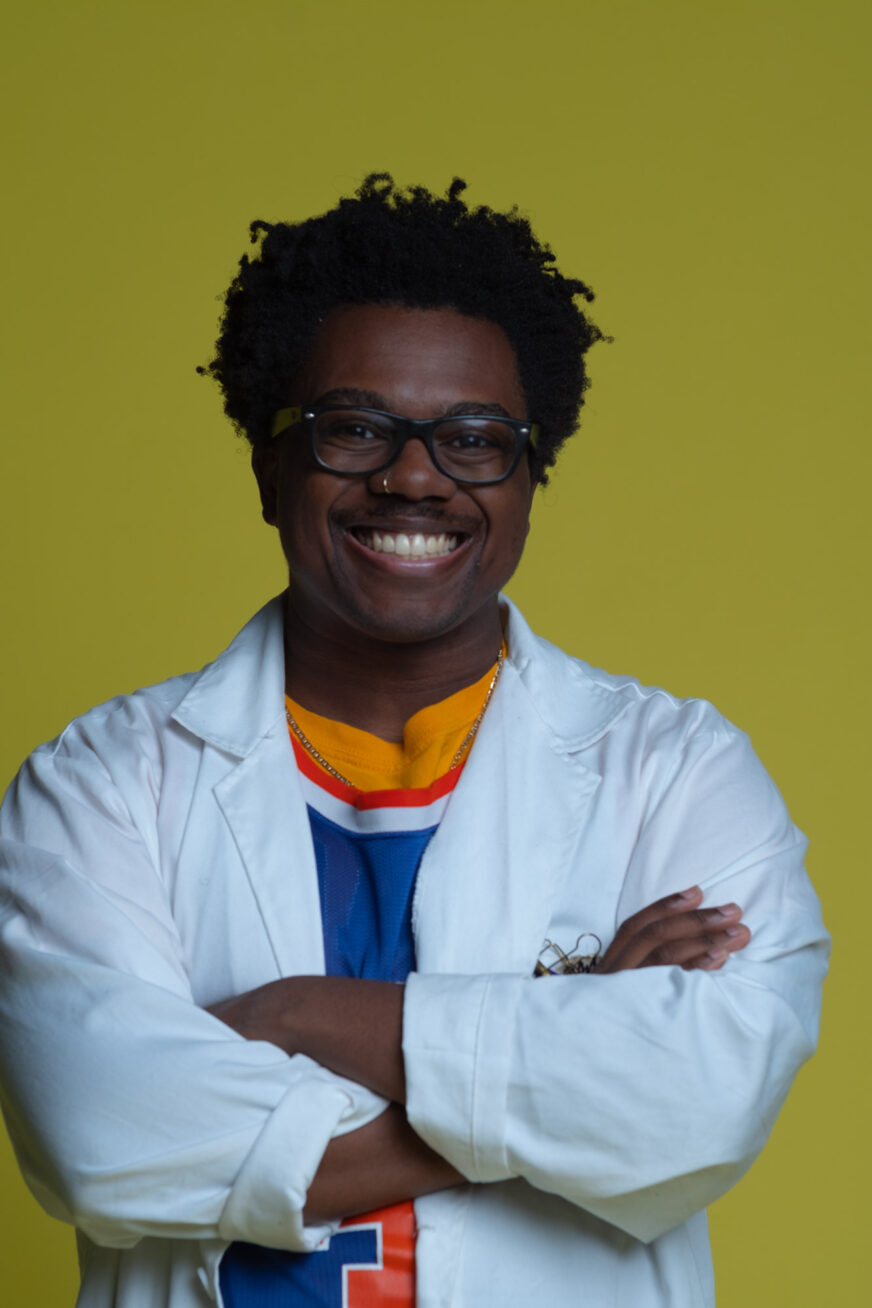 A person standing in front of a solid green background.