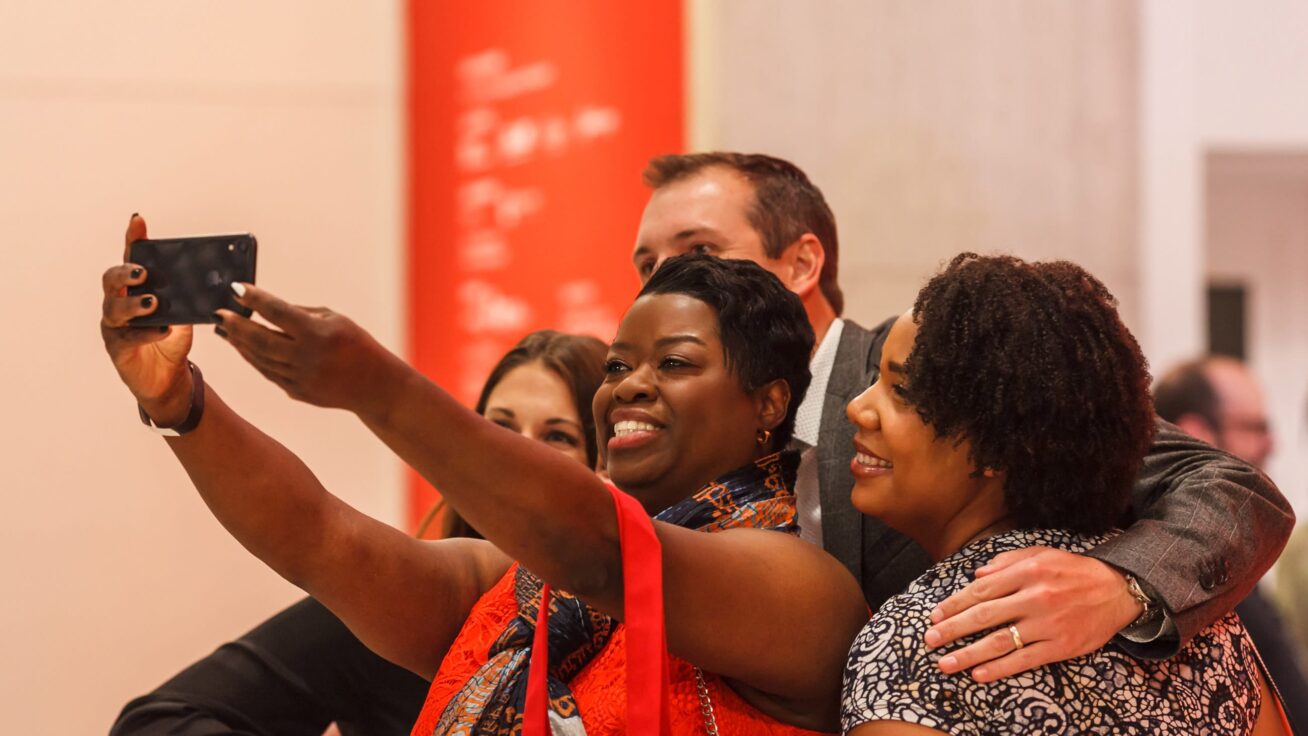 A group of four people huddled together taking a selfie.