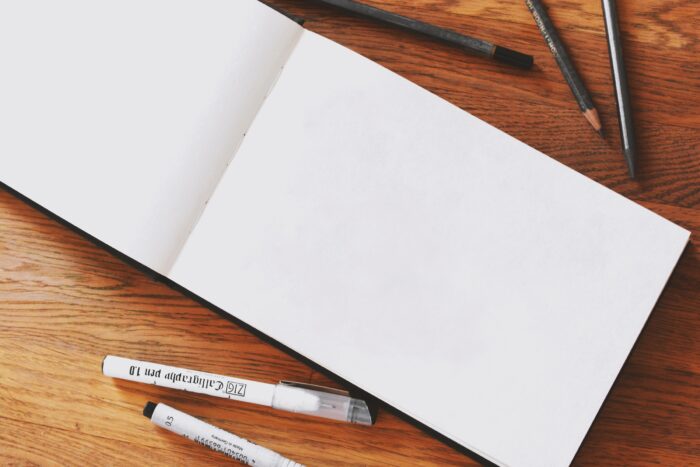 Photo of a blank notebook with pens around it