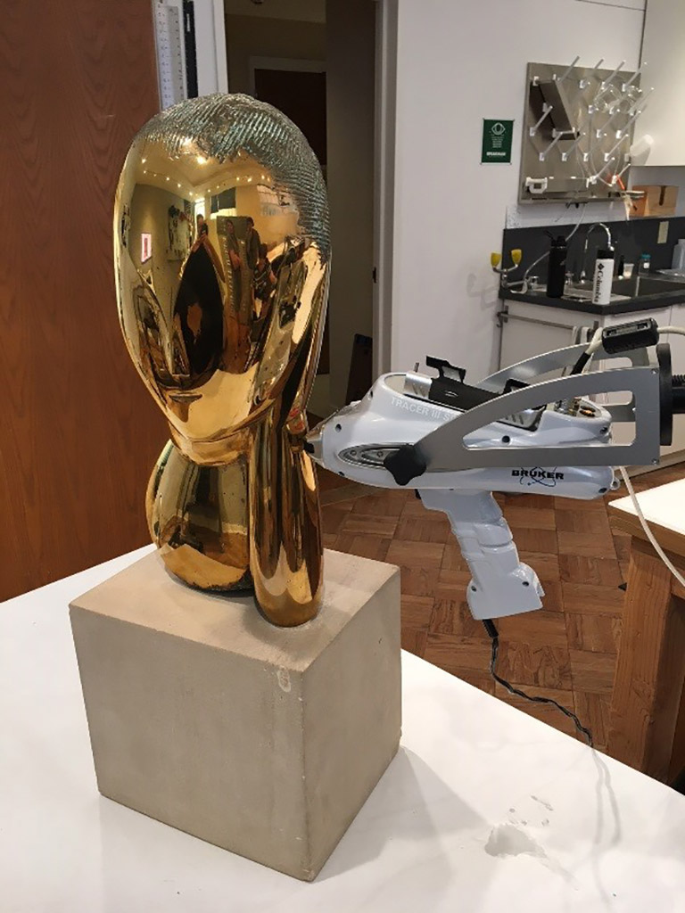 A bronze sculpture sitting on a table in a conservation lab.