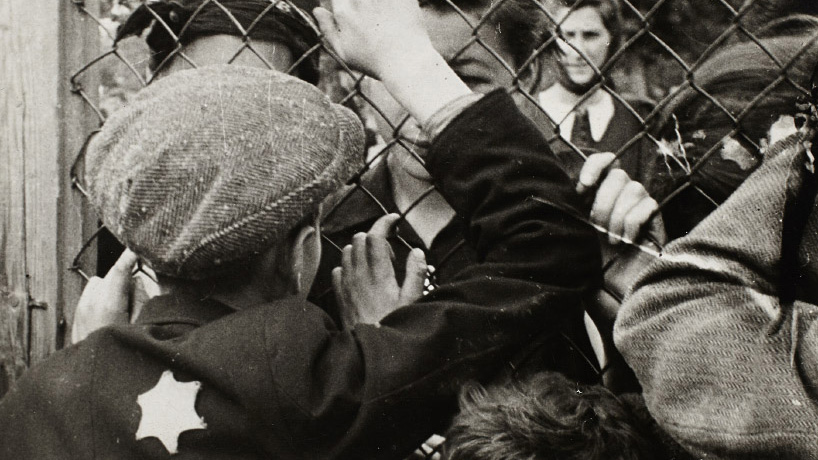 Black and white photograph of children talking through a fence