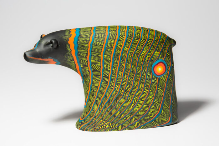 Glass sculpture of a bear with bright green, orange, and blue line patterns