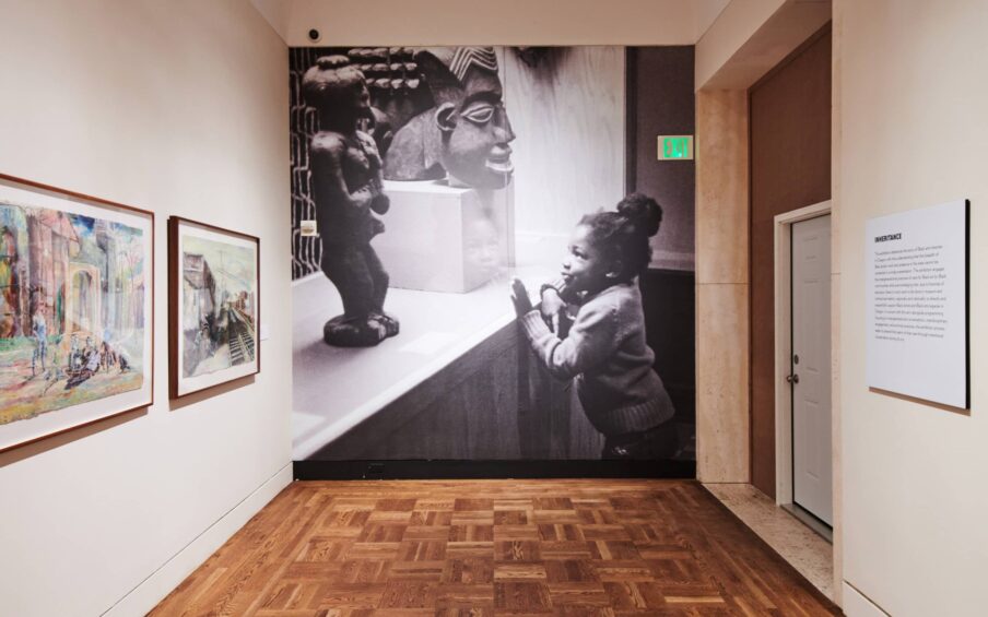 Large black and white photograph of a child looking at a sculpture.