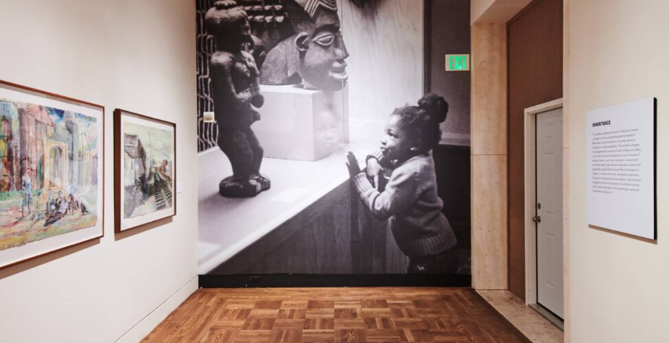 Large black and white photograph of a child looking at a sculpture.