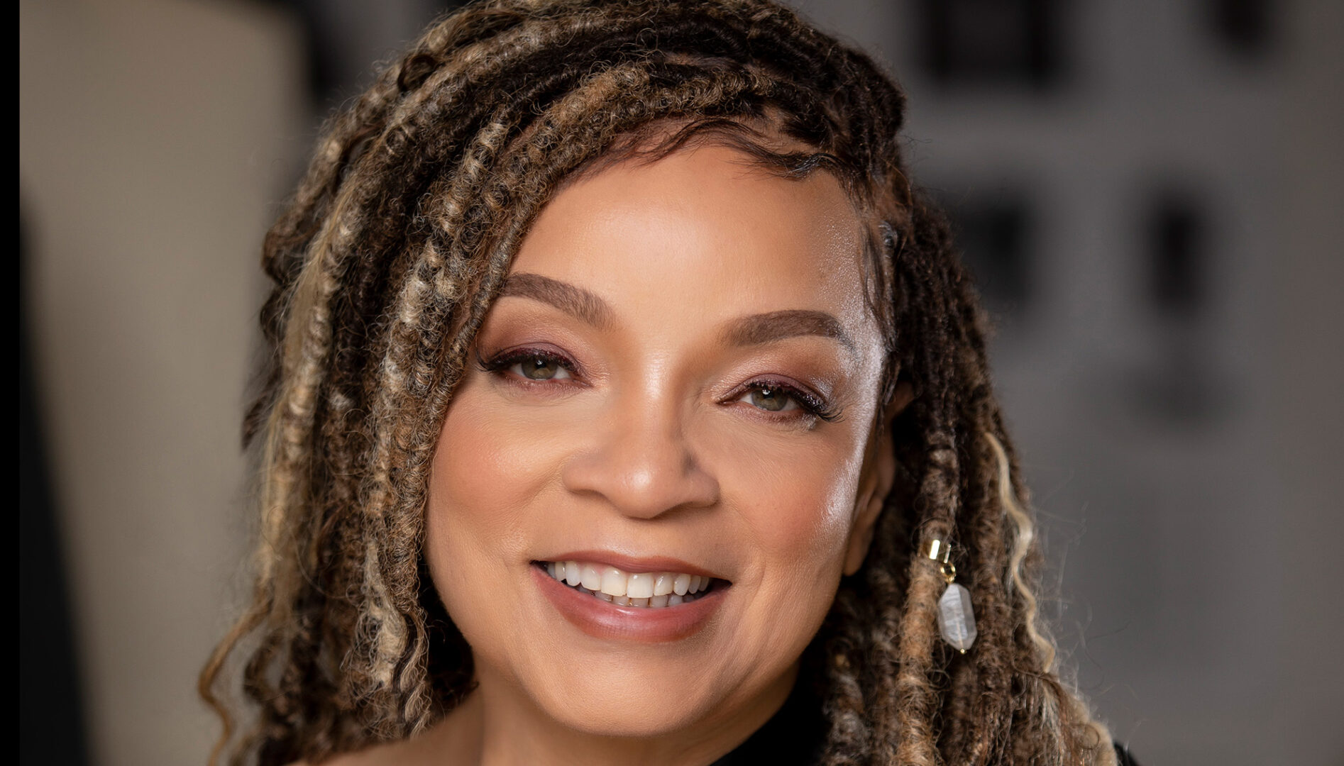 Photo of a smiling Black woman with dreadlocks
