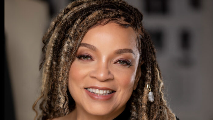 Photo of a smiling Black woman with dreadlocks