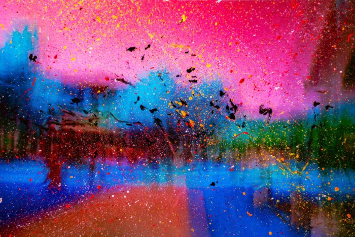 Abstract image with neon pink and blue background and paint splatters in the foreground