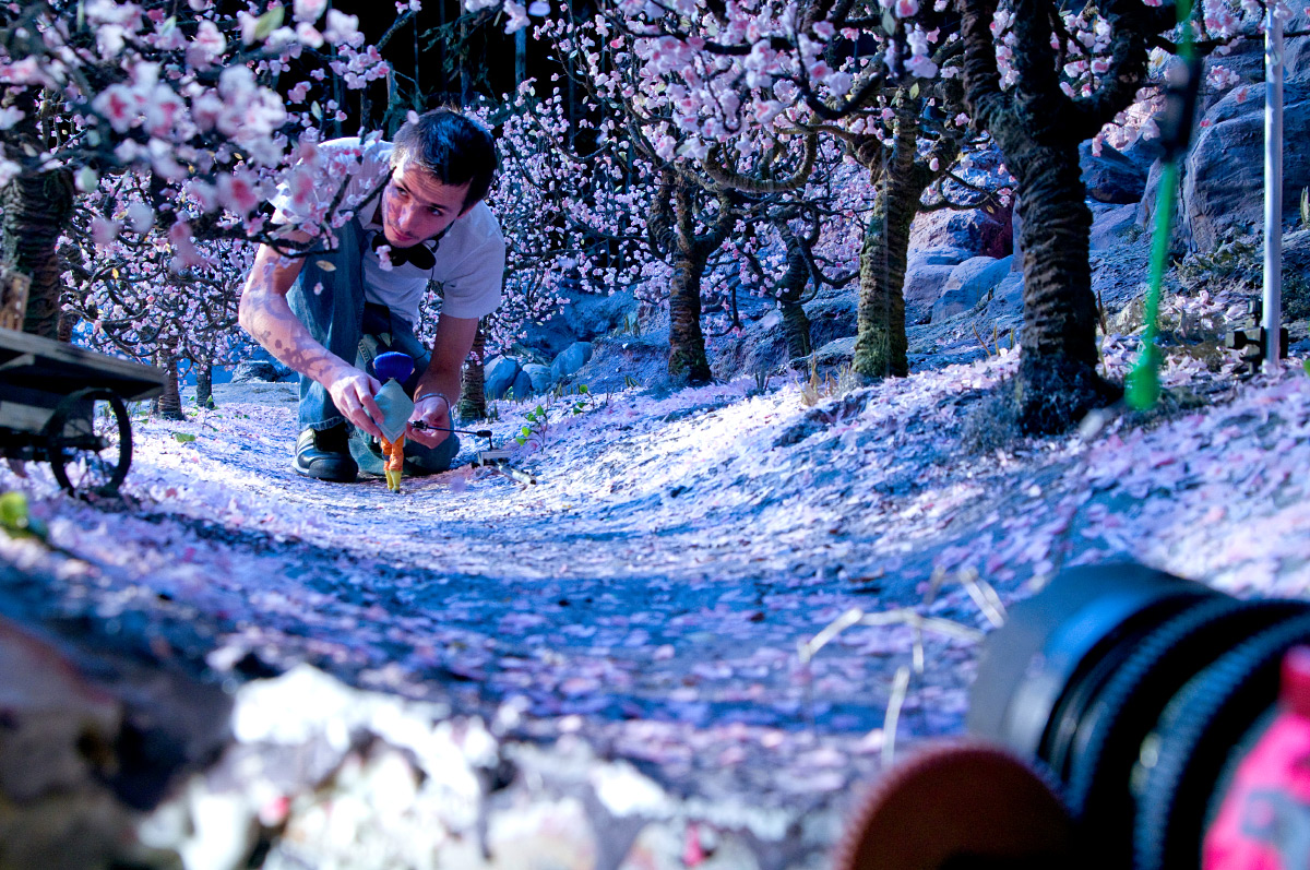 Photo of a person crawling through a film set of miniature trees from the movie Coraline