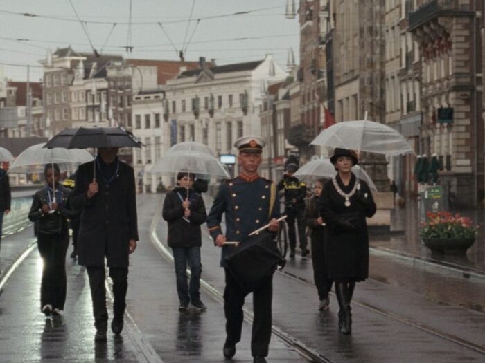 Film still from Occupied City of a group of people walking down a rainy city street