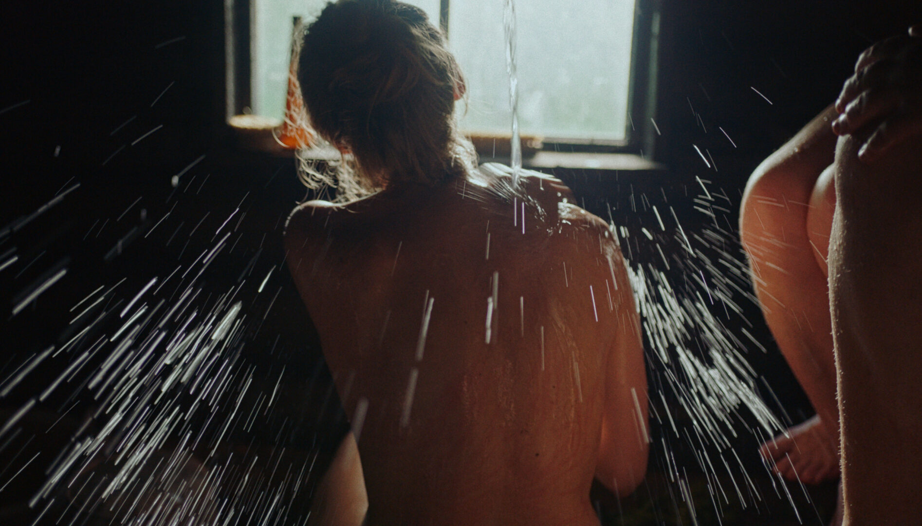 Photograph of a woman's back with water being poured over her from above