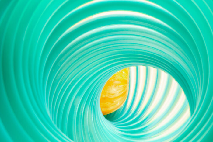 Abstract image of a green slinky-like object with a yellow-orange squash inside of it