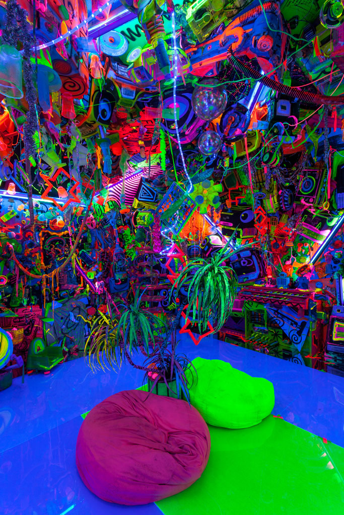 Photo of a dark room filled with day glo objects with bean bags on the floor.