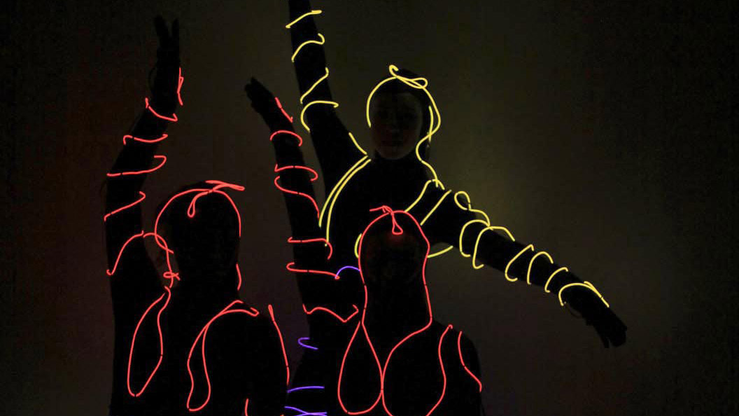 People wearing neon lights in dance positions.