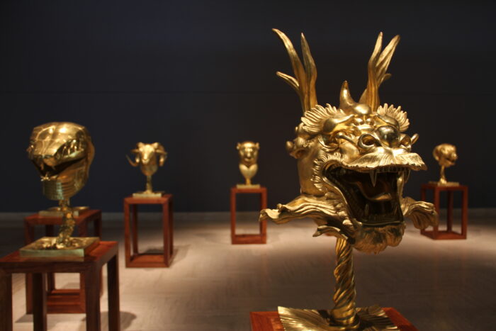 Photograph of a dim gallery with statues of golden heads