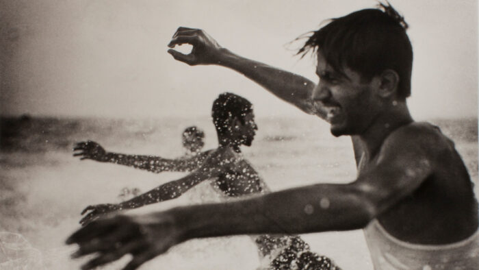 Sepia toned photo of men playing in the surf
