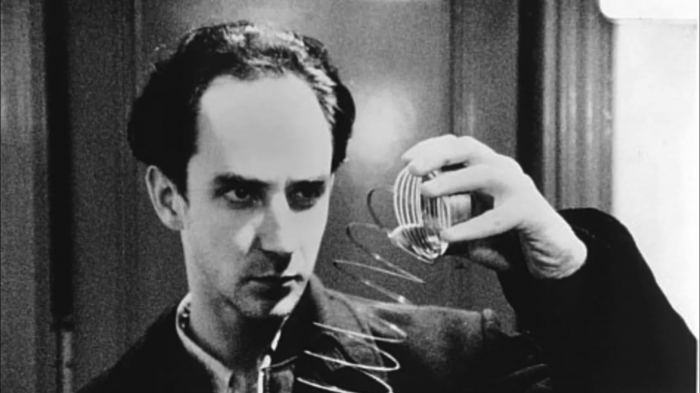 Black and white film still from the movie Pi of a man staring at a Slinky