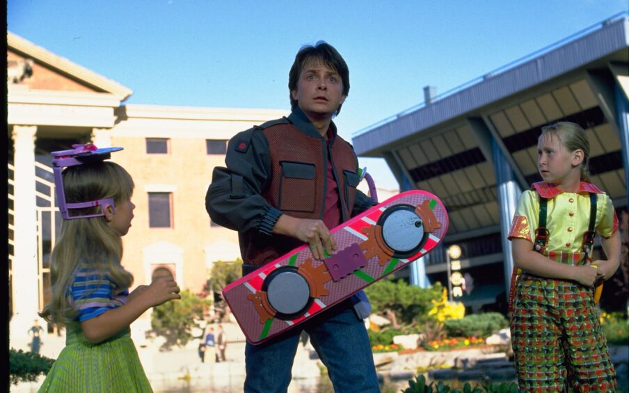 Photo of a man holding a skateboard with two young girls to either side looking at him