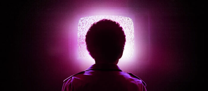 Outline of the back of a person's head looking at a glowing pink television