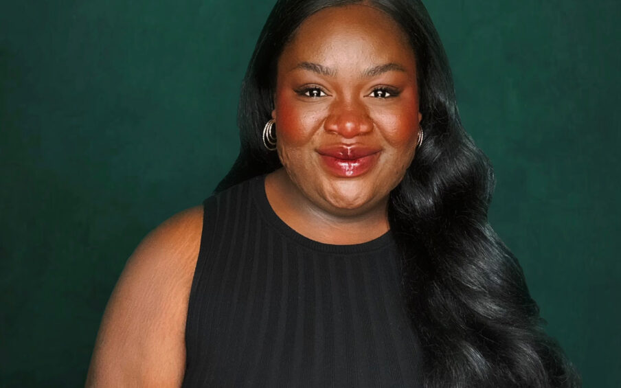 Portrait of a smiling Black woman with long hair wearing a black sleeveless shirt