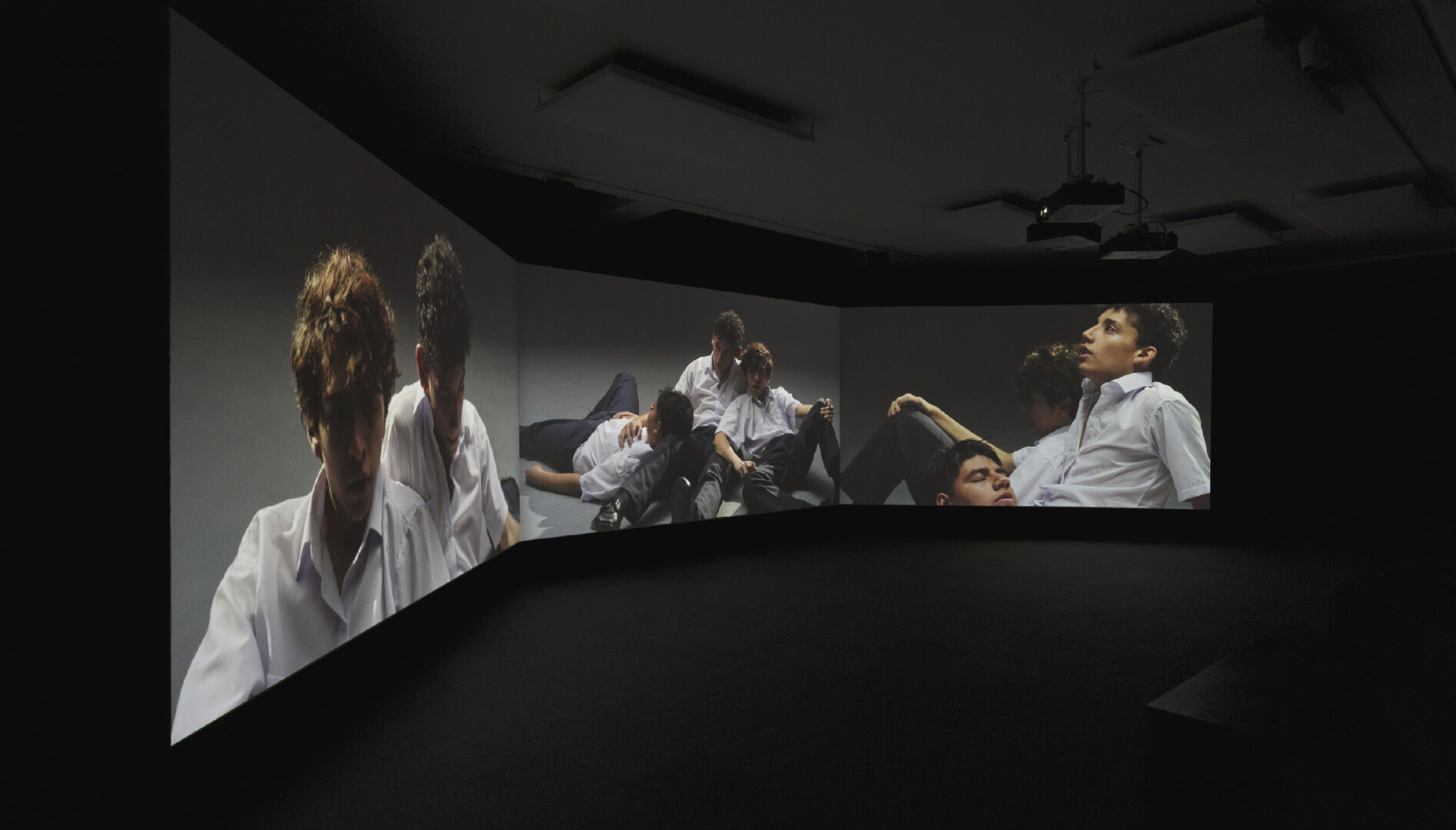 Multiple large screens displaying images of peoeple in white suits.