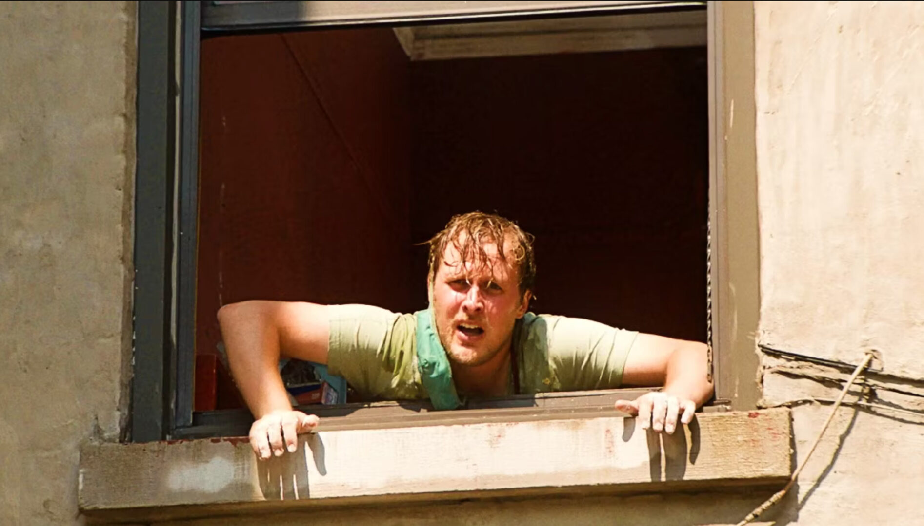 A man with red short hair hanging out a window