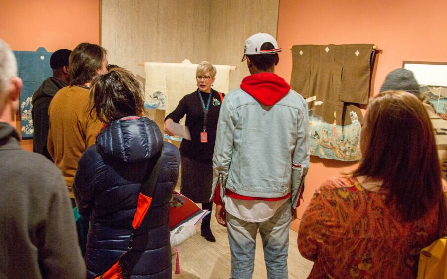 A tour guide talking to a group of visitors in a gallery.
