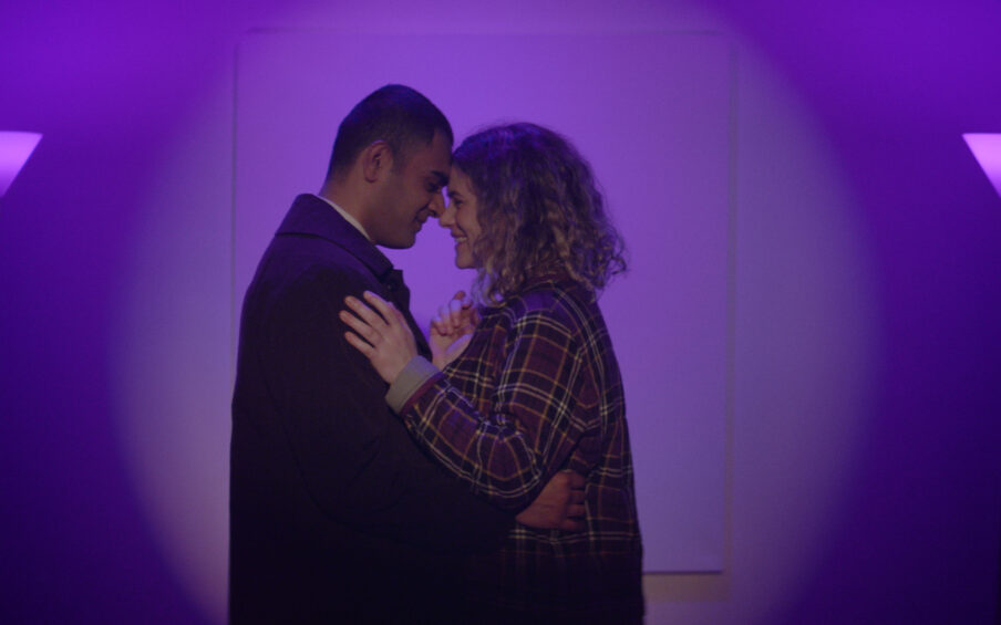 Photo still of a couple hugging surrounded by purple light