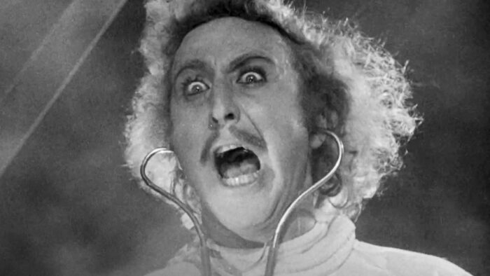 Black and white film still from Young Frankenstein, of Gene Wilder wearing a stethoscope and yelling