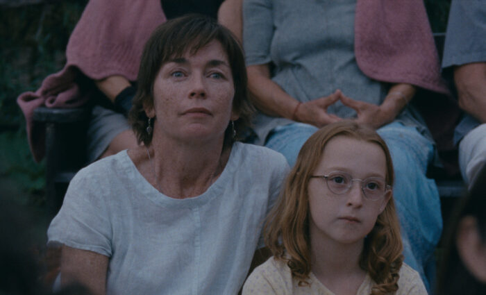 Photo of a woman with short hair and a girl with long red hair and eyeglasses sitting next to each other