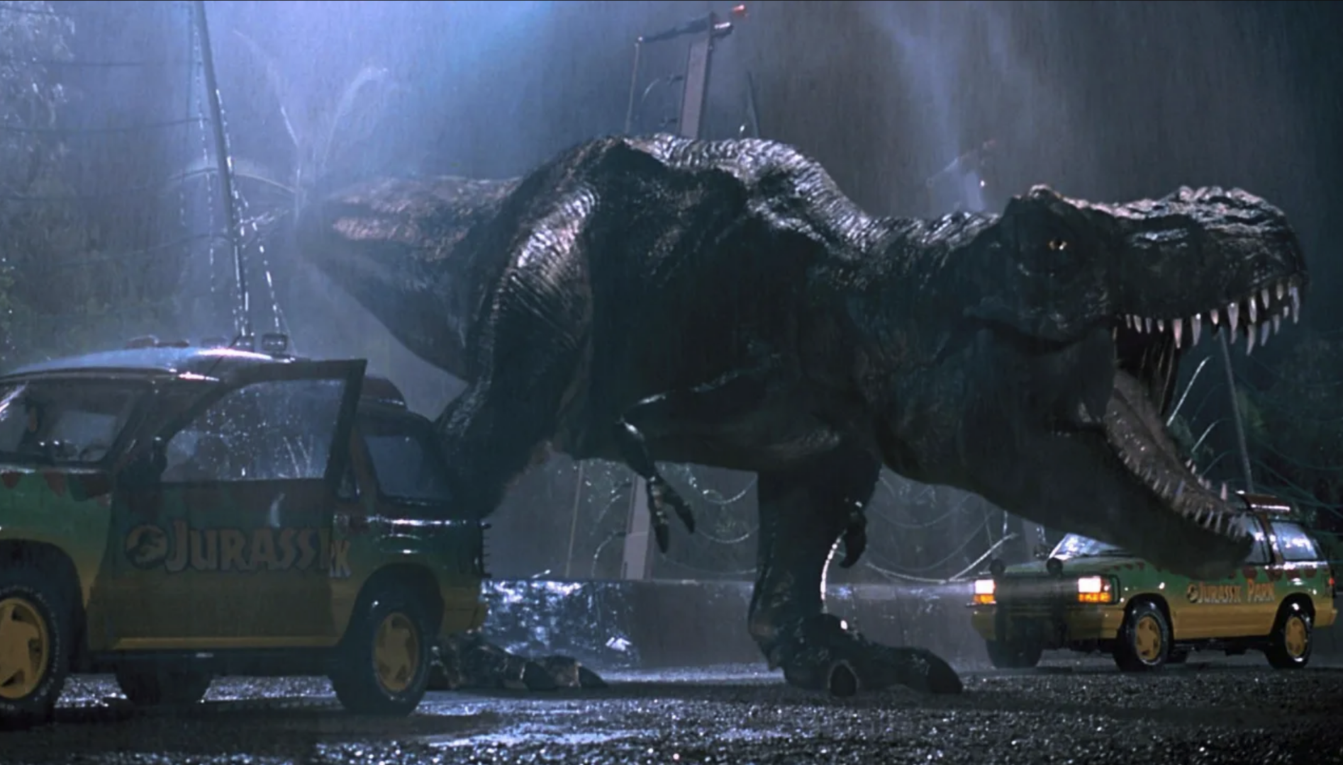 Film still of a T Rex dinosaur roaring surrounded by cars